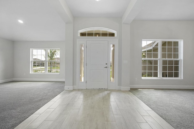 entryway featuring light carpet and beam ceiling