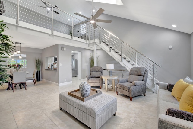 living room with ceiling fan and a towering ceiling