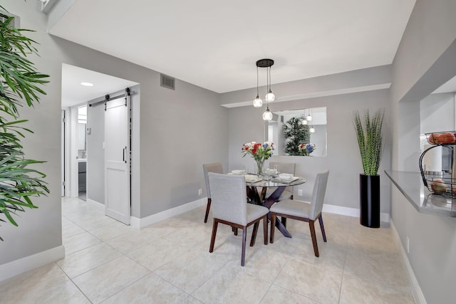 dining room featuring a barn door and light tile patterned floors