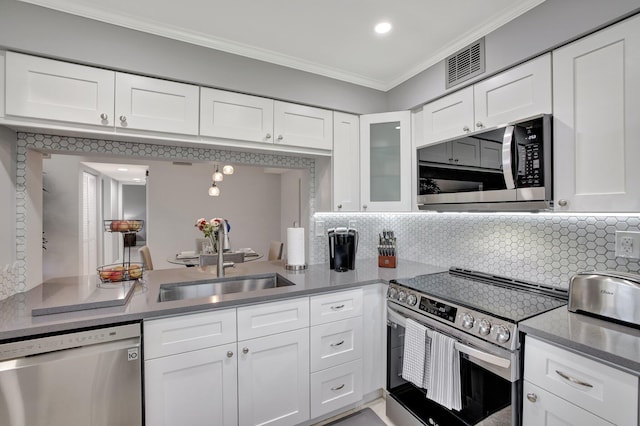 kitchen with sink, tasteful backsplash, appliances with stainless steel finishes, white cabinets, and ornamental molding