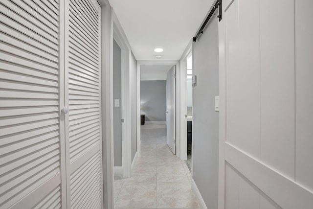 hall featuring light tile patterned floors and a barn door