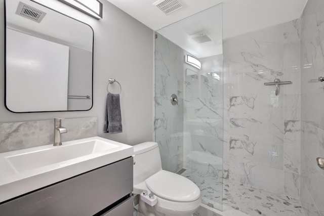 bathroom featuring tiled shower, vanity, and toilet