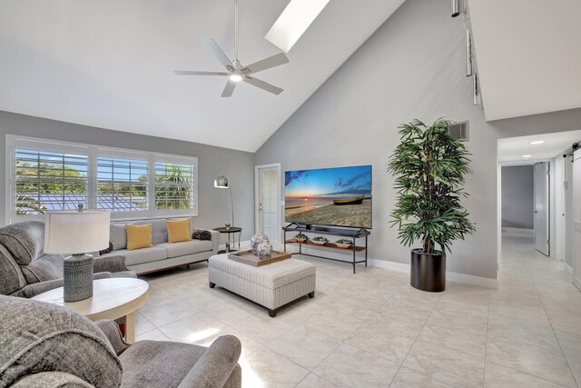 living room with ceiling fan, a barn door, light tile patterned flooring, and high vaulted ceiling