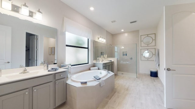 bathroom with plus walk in shower, hardwood / wood-style floors, and vanity