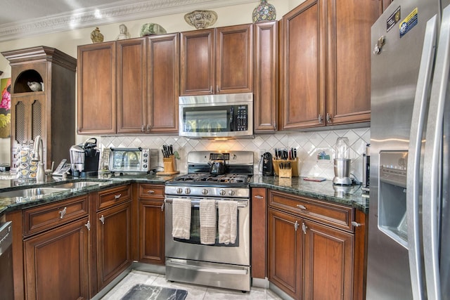 kitchen with backsplash, sink, dark stone counters, and appliances with stainless steel finishes