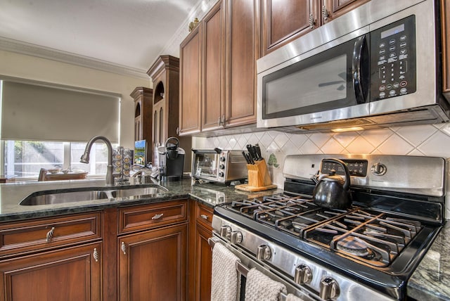 kitchen featuring sink, stainless steel appliances, backsplash, crown molding, and dark stone counters