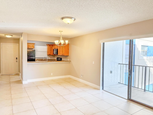 empty room with light tile patterned flooring, a textured ceiling, an inviting chandelier, and sink