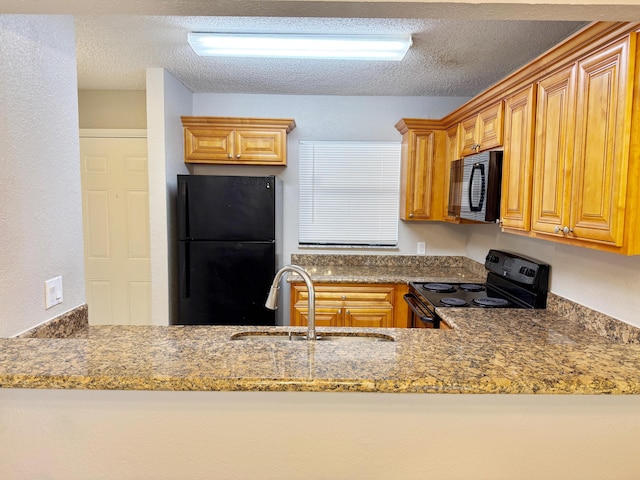 kitchen featuring light stone counters, sink, black appliances, and a textured ceiling