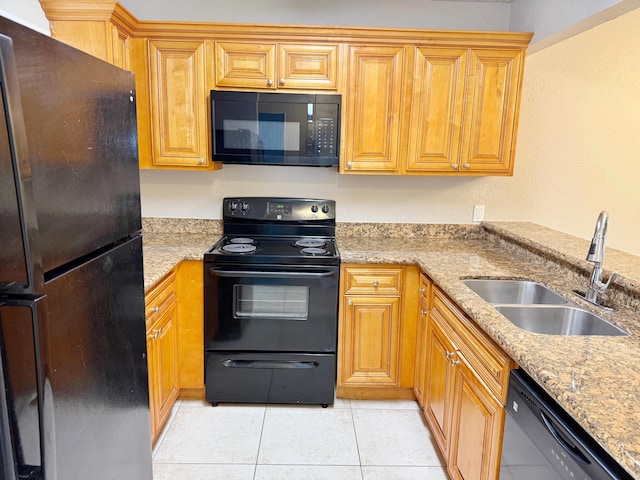 kitchen with black appliances, light tile patterned flooring, light stone counters, and sink