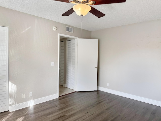 unfurnished bedroom featuring a textured ceiling, a closet, ceiling fan, and dark wood-type flooring