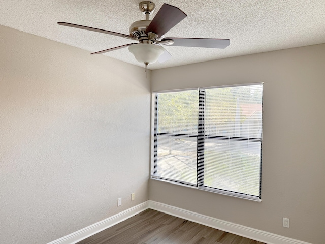 spare room featuring a textured ceiling, dark hardwood / wood-style flooring, ceiling fan, and a healthy amount of sunlight