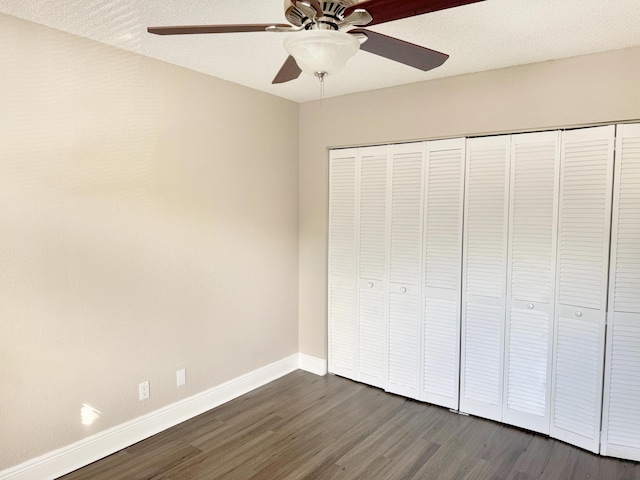 unfurnished bedroom with ceiling fan, dark hardwood / wood-style floors, a textured ceiling, and a closet