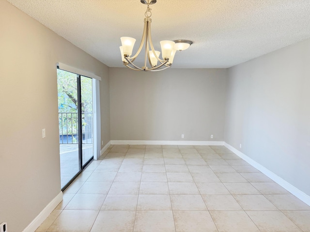 tiled empty room with a textured ceiling and an inviting chandelier