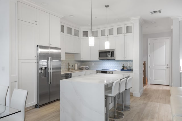 kitchen featuring white cabinets, appliances with stainless steel finishes, backsplash, and a center island