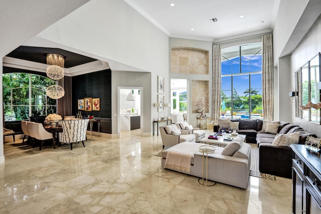 living room featuring a chandelier, a towering ceiling, and crown molding