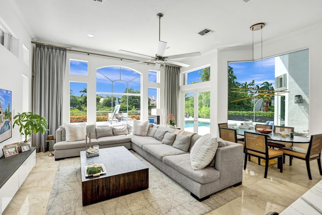 living room with ceiling fan, ornamental molding, and a high ceiling