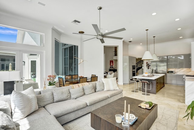 living room with ceiling fan and ornamental molding