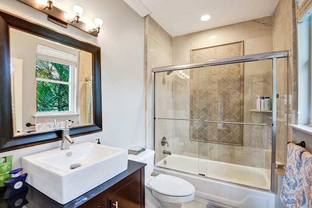 full bathroom featuring combined bath / shower with glass door, vanity, and toilet