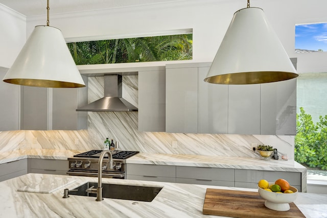 interior space with wall chimney exhaust hood, tasteful backsplash, light stone counters, decorative light fixtures, and gray cabinets