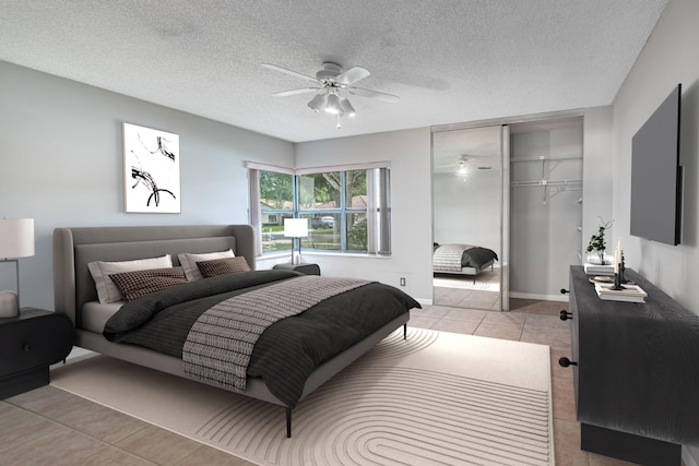 bedroom featuring ceiling fan, light tile patterned flooring, a textured ceiling, and a closet