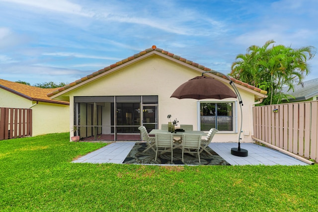 rear view of property with a yard, a patio, and a sunroom