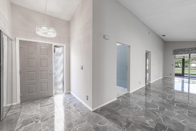 entryway featuring a textured ceiling, high vaulted ceiling, and a chandelier