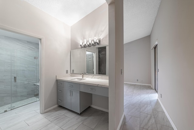 bathroom with a textured ceiling, vanity, and walk in shower