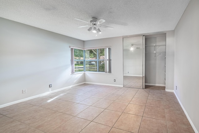 unfurnished bedroom featuring ceiling fan, a closet, light tile patterned floors, and a textured ceiling