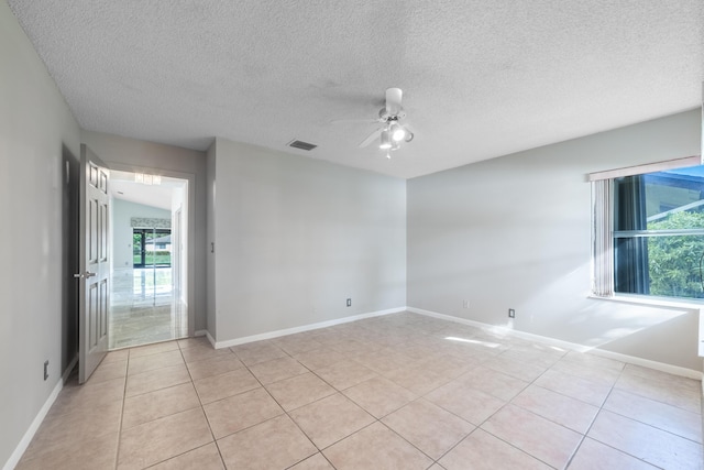 empty room featuring a textured ceiling, ceiling fan, light tile patterned floors, and vaulted ceiling