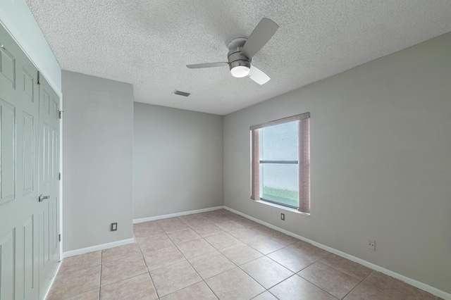 unfurnished bedroom featuring ceiling fan, a closet, light tile patterned flooring, and a textured ceiling