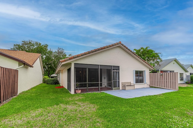 rear view of house featuring a sunroom, a yard, and a patio