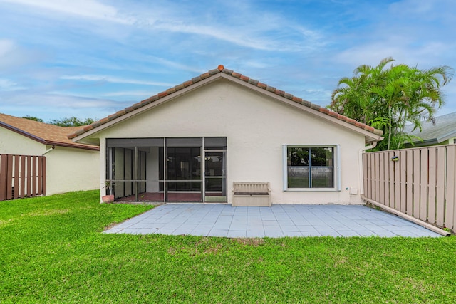 back of property featuring a patio, a lawn, and a sunroom