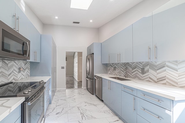 kitchen featuring a skylight, sink, stainless steel appliances, and blue cabinets