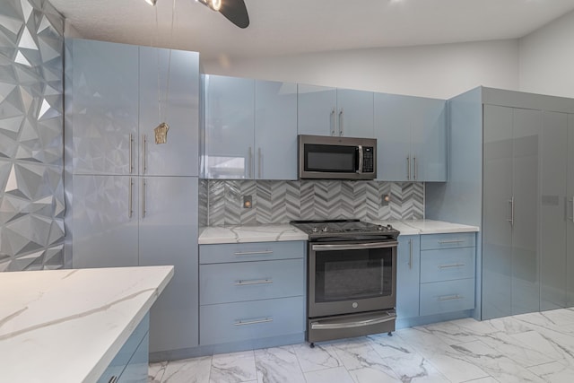 kitchen featuring light stone countertops, backsplash, stainless steel appliances, ceiling fan, and blue cabinetry