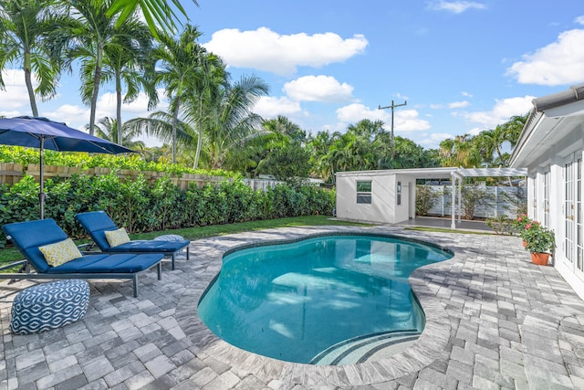 view of swimming pool with a patio area, an outdoor structure, and a pergola