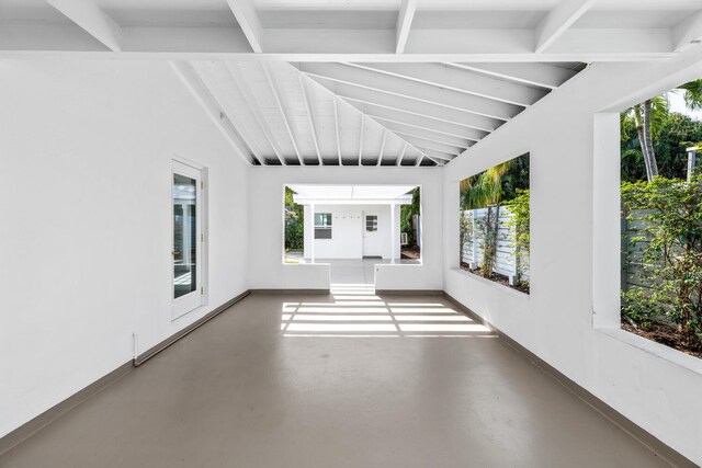 unfurnished room with plenty of natural light and lofted ceiling with beams