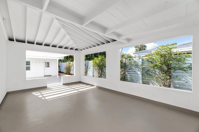 unfurnished sunroom featuring vaulted ceiling with beams and a healthy amount of sunlight