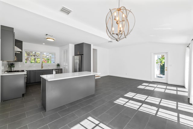 kitchen featuring gray cabinets, appliances with stainless steel finishes, hanging light fixtures, and dark tile patterned flooring