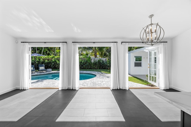 doorway with an inviting chandelier, tile patterned flooring, and plenty of natural light