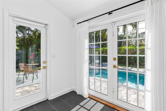 entryway with french doors, plenty of natural light, vaulted ceiling, and dark tile patterned flooring