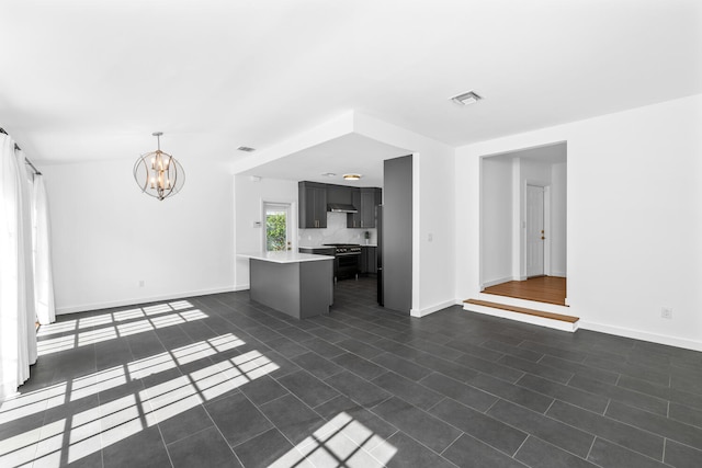 unfurnished living room with dark tile patterned floors and an inviting chandelier