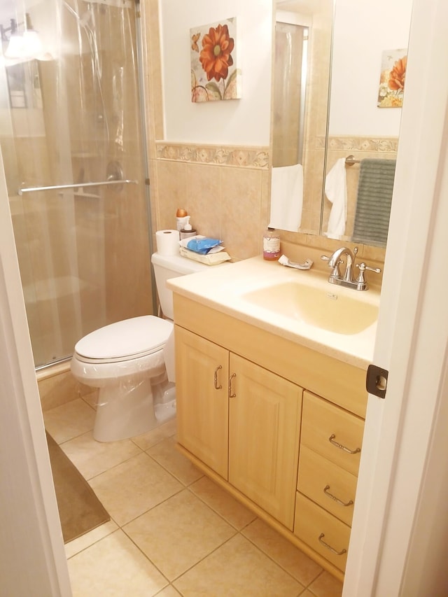 bathroom with vanity, tile patterned floors, toilet, tile walls, and a shower with shower door