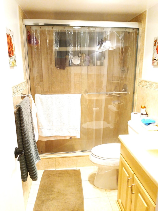 bathroom featuring vanity, tile patterned floors, toilet, tile walls, and an enclosed shower