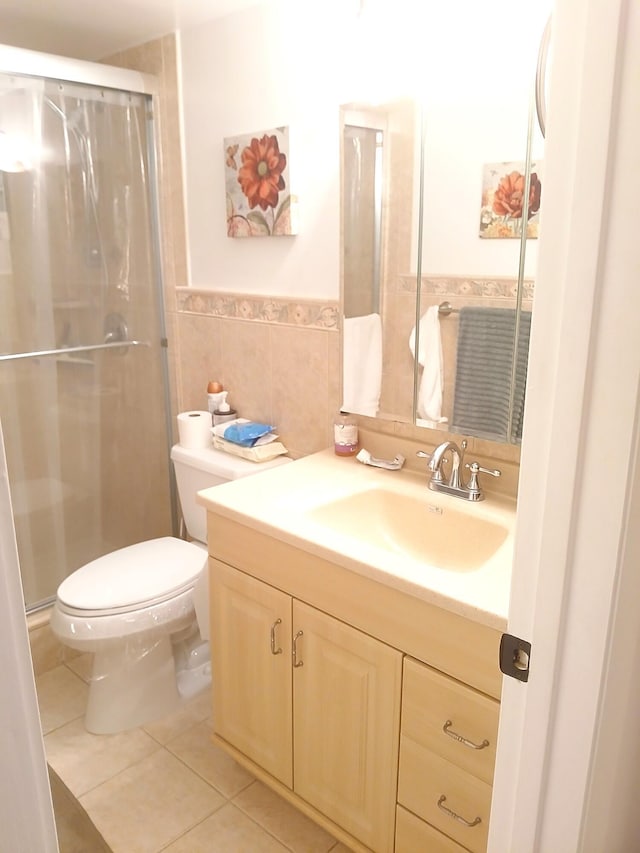 bathroom with tile patterned flooring, an enclosed shower, toilet, vanity, and tile walls