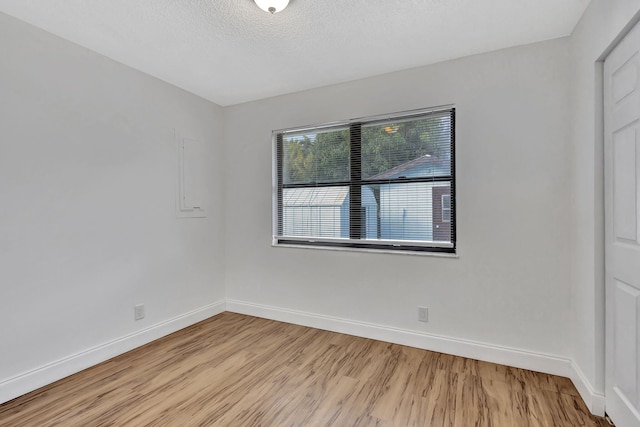 spare room featuring light hardwood / wood-style floors and a textured ceiling