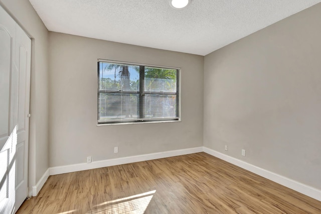 unfurnished room with light wood-type flooring and a textured ceiling