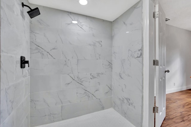 bathroom with a tile shower and hardwood / wood-style flooring