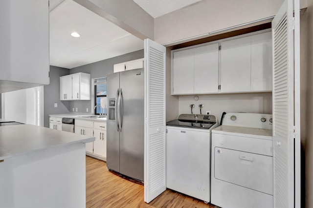 laundry room featuring washer and dryer, light hardwood / wood-style floors, cabinets, and sink