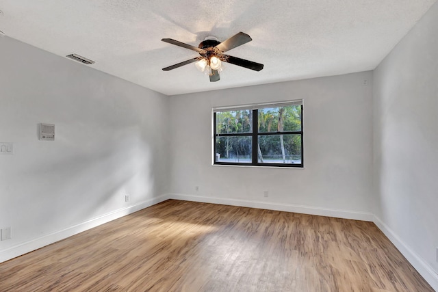 empty room with a textured ceiling, light wood-type flooring, and ceiling fan