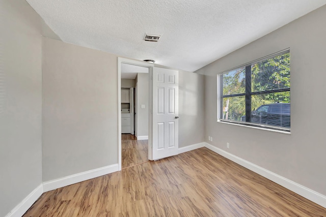 empty room featuring light hardwood / wood-style floors and a textured ceiling